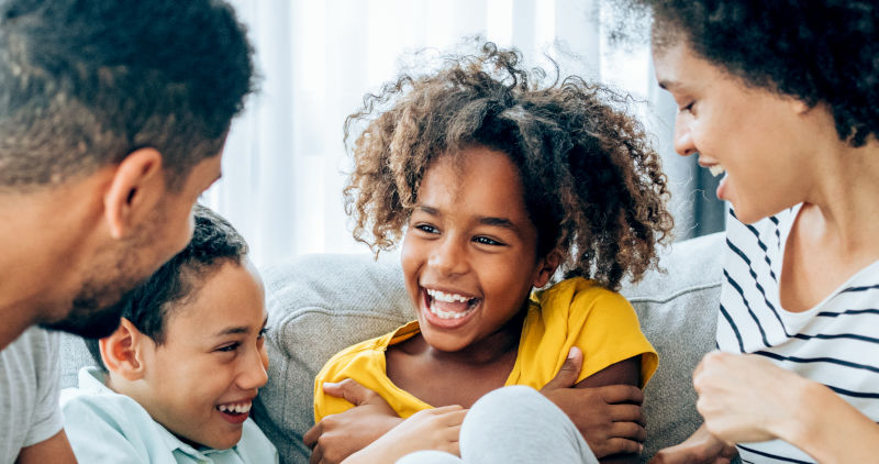 Family with children laughing on a couch