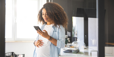 A happy, expectant mother looking at her smartphone.