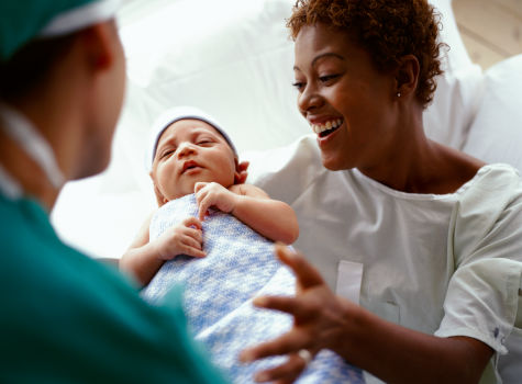 A woman in a hospital gown holding a baby.