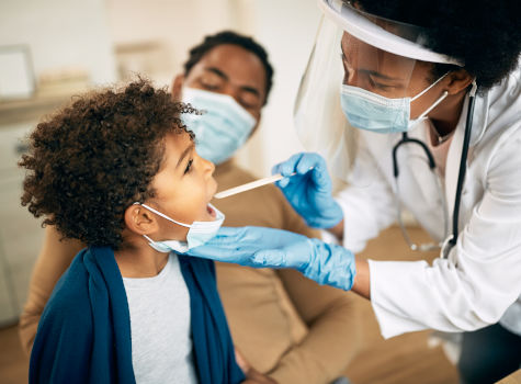A doctor examining the throat of a small boy.