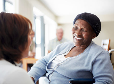 A caregiver talking to a wheelchair-bound patient.