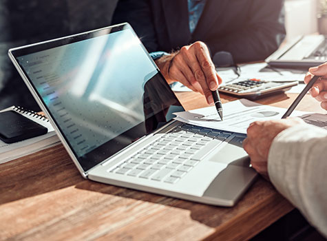 Hands using a computer with various reports visible