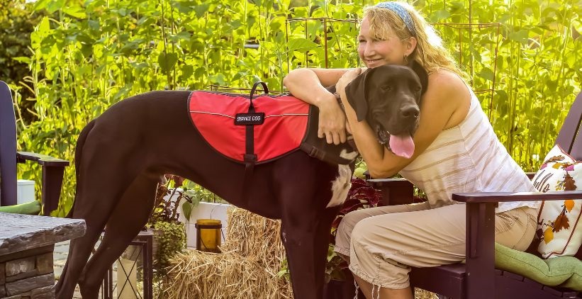 woman outside holding her service dog in a field