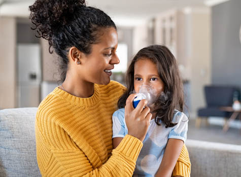 A mom helping her daughter with asthma use her inhaler