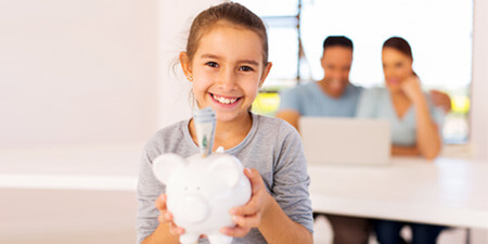 Happy child with a piggybank enjoying a morning with her parents