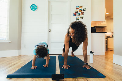 A daughter and mom practicing yoga at home -- we offer free yoga programs.