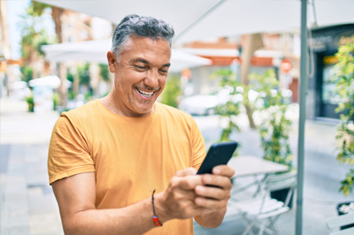 A happy man, using the Optima Health mobile app while he's on the go.